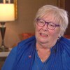 Martine Galibois-Barss est assise sur une chaise avec des coussins rouges et une lampe en arrière-plan.