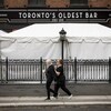Deux femmes marchent devant un bar de Toronto dont la terrasse a été couverte.