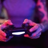 Une personne est assise sur un sofa et joue à un jeu vidéo.