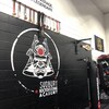 L'un des murs à la Sudbury Kickboxing Academy où l'on voit le logo de l'entreprise, des médailles et de l'équipement sportif.