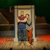 Deux hommes debout devant un cadre de porte dans un décor de théâtre