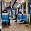Deux personnes, dont une masquée, sont assises à bonne distance dans un wagon de métro vide.