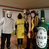Quatre personnes costumées en chef cuisinier, en flacon de moutarde, en hot-dog et en bouteille de bière à l'occasion de la mi-carême dans une maison de Natashquan.