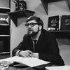 Dans un studio de télévision, l'animateur Michel Garneau, assis à son bureau.