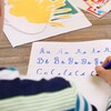 Un enfant recopie dans un cahier les lettres A, B et C.