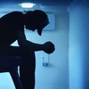 Un jeune homme pensif assis sur une chaise dans la pénombre.