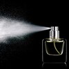 Du parfum vaporisé jaillissant d'une bouteille. 