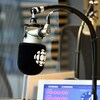 Gros plan sur un micro avec le logo de Radio-Canada dans un studio de radio.