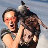 Jeneda Benally réagit de manière heureuse et surprise en tenant son chien, un chinois à crête de 17 ans, sans ses bras.