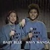 Deux femmes portant le même chandail bleu tiennent chacune un micro à la main. 
