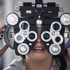 Vue de face d'une jeune personne effectuant un examen de la vue dans une clinique.