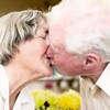 Une femme et un homme aînés se donnent un bisou sur la bouche.