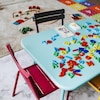 Une petite table pour enfants est recouverte d'un jeu avec des chiffres et des lettres dans une salle qui accueille des enfants.