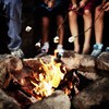 Des enfants font griller des guimauves au-dessus des flammes.
