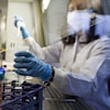 Une femme manipule un tube et une pipette. 