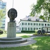 La tête en bronze de Riel trône devant un édifice historique.                        