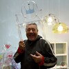 Le designer Philippe Starck prend la pose, riant, avec une chaise transparente sur la tête.