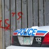 Une voiture de police devant une clôture sur laquelle on peut voir les deux lettres associés au gang de rue Terror Squad, à Saskatoon.
