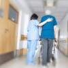 Une préposée aide un patient à circuler dans un corridor d'une résidence pour personnes âgées.