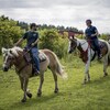 Deux jeunes sur des chevaux dans un camp de jour équestre.
