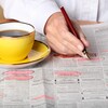 Une personne consulte les petites annonces d'un journal pour y trouver un emploi. 