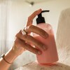 Une main s'empare d'un pot de revitalisant dans la douche.