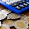 Des pièces de 2 dollars canadiens sur une table, à côté d'une calculatrice.