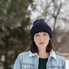 Elle porte une tuque bleue et un veston en jeans. 