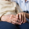 Une aidante tient les mains d'une ainée.