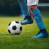 Plan en dessous des genoux d'un joueur de soccer, qui a le pied sur un ballon.