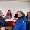 Trois hommes et deux femmes assis autour d'un table sous un chapiteau posent pour une photo