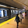 Des gens marchent sur le quai d'une station de métro pendant qu'un train passe.
 
