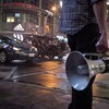 Un assistant tient un porte-voix près de la rue Yonge où est tournée une scène du film Suicide Squad avec une voiture.