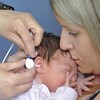 Un nouveau-né dans les bras de sa maman qui passe un test de dépistage de la surdité.