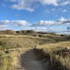 Paysage des prairies en septembre, à la fin de l'été, badlands à l'horizon sous un ciel bleu avec nuages.
