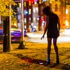 Une jeune femme seule au coin d'une rue d'une grande ville la nuit, avec un téléphone portable tombé au sol.