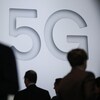 Des gens marchent devant une réclame publicitaire de la 5G au Mobile World Congress, à Barcelone, en février 2018.