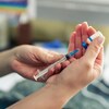 Gros plan sur les mains d'une personne manipulant une seringue et une fiole de vaccin contre la COVID-19. 