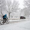 Une personne roule à vélo pendant une tempête de neige à Montréal.