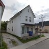 Une maison allumette blanche sur le coin d'une rue.