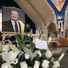 Une gerbe de fleurs se trouve devant la photo d'un homme dans une église.