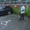 Dany marche avec une canne sur un stationnement.