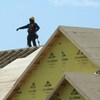 Un ouvrier de la construction sur le toit d'une maison en chantier.