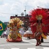 Deux femmes avec des costumes colorés et un drapeau du Brésil dansent.