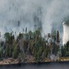 Un hélicoptère relâche sa cargaison d'eau sur une forêt en feu.