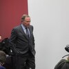 Un homme marche dans une salle remplie de médias.