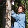 Geneviève accroche des drapeaux sur un arbre.