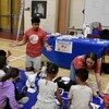 Des enfants participent à une présentation sur les soins hospitaliers dans un gymnase.