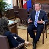 Le premier ministre de l'Alberta assis dans son bureau en face d'une journaliste à qui il accorde une entrevue.