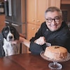 Horacio Arruda devant un gâteau au chocolat, en compagnie de son chien.